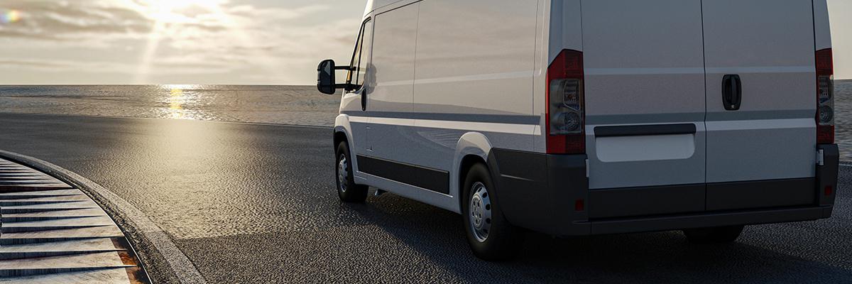 Van driving down a road near the sea